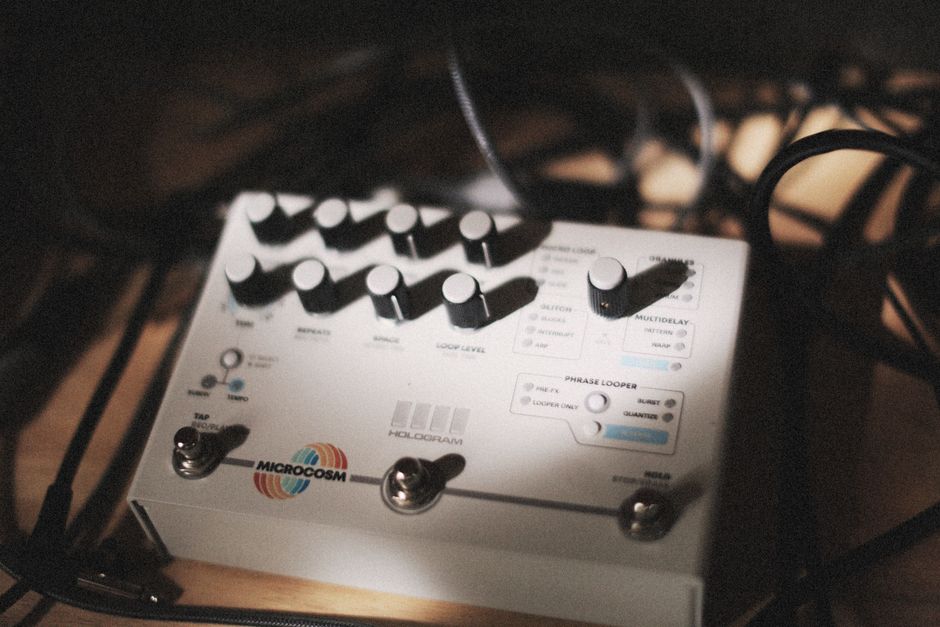 Close-up of audio effects pedal surrounded by cables in a dimly lit music studio, showcasing music technology.